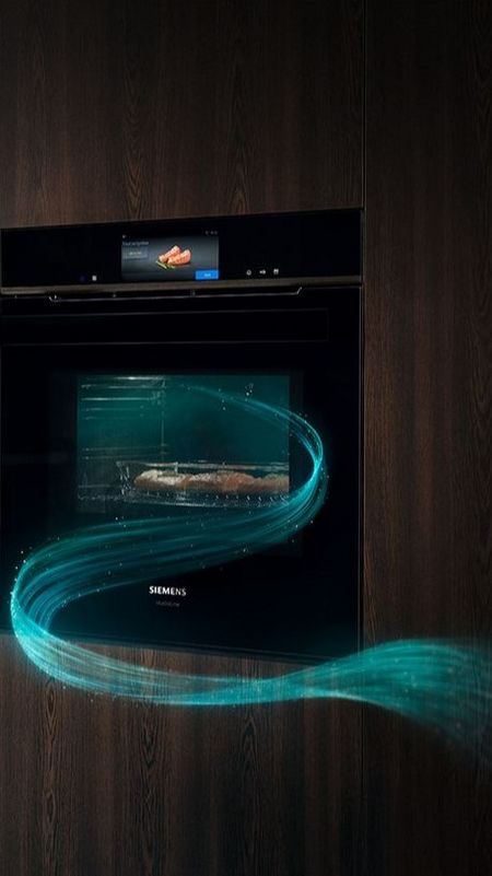 Una elegante cocina negra de Siemens que muestra un horno y un microondas integrables, con una pantalla de cocci&oacute;n iluminada en azul.