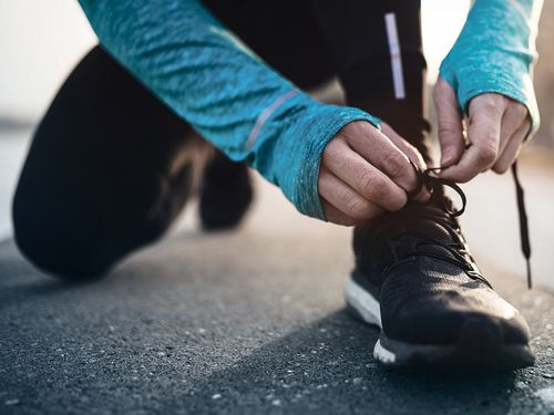 Adidas - Mann bindet sich Schuh in Sportsachen zu