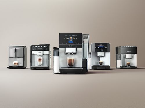 Vier verschiedene Kaffeevollautomaten stehen nebeneinander auf einem Tisch.