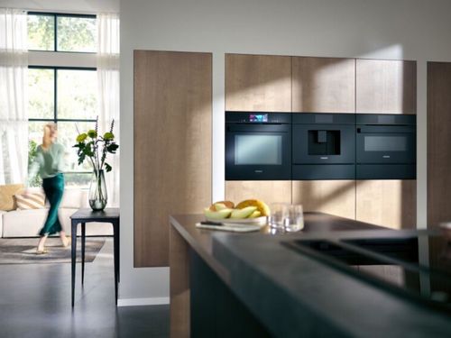 De man staat voor het raam in de moderne keuken met uitzicht op de stad.