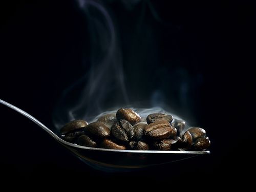 En sked med rykande kaffebönor 