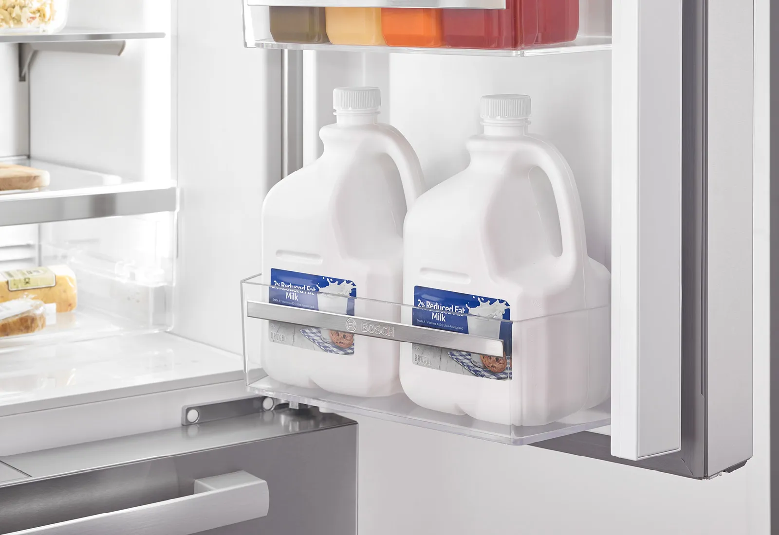 Bosch fridge door with two milk jugs and juice containers in shelves.
