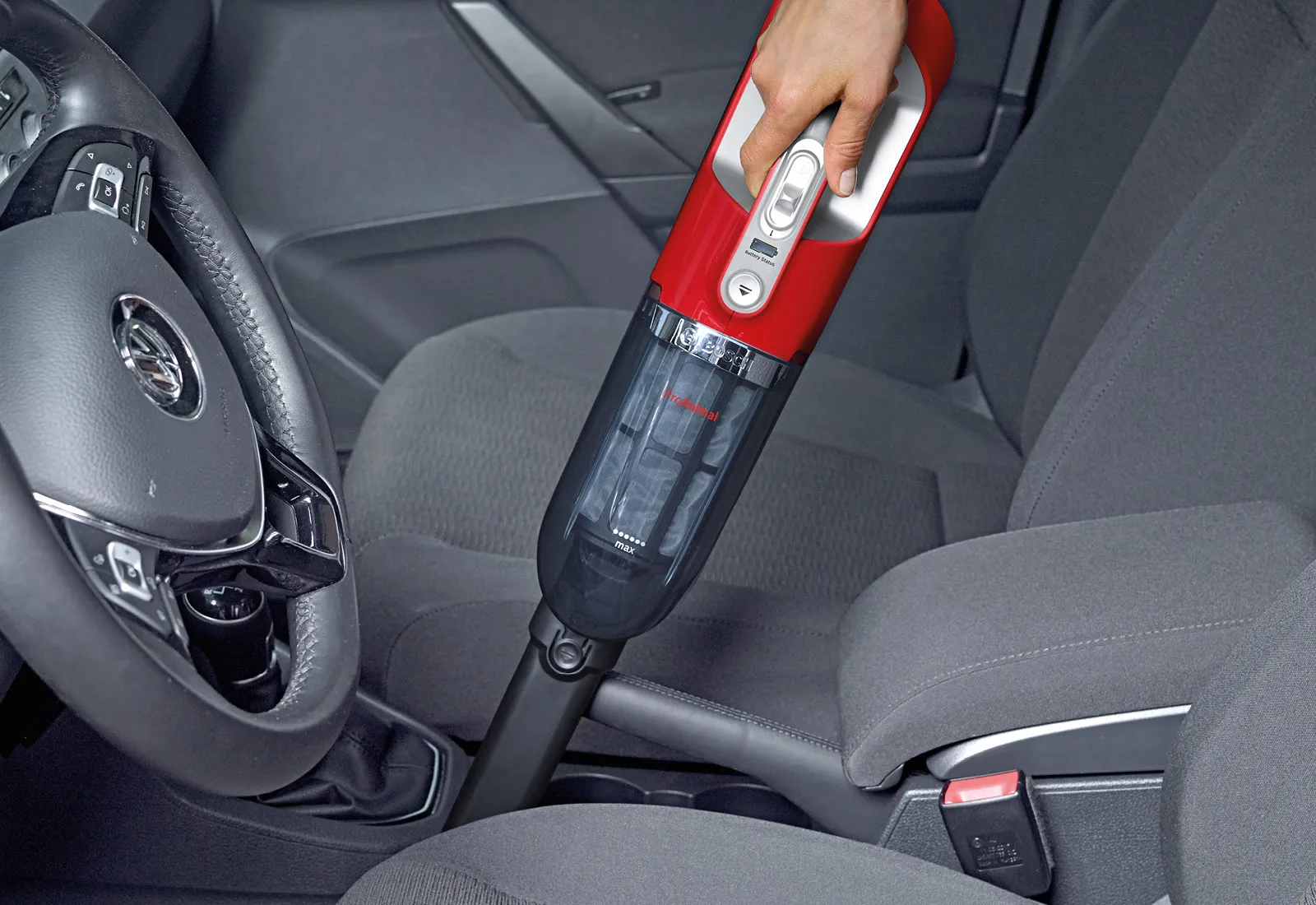 Aspirator portabil folosit pentru a curăța interior auto, cu volan și scaun vizibil.
