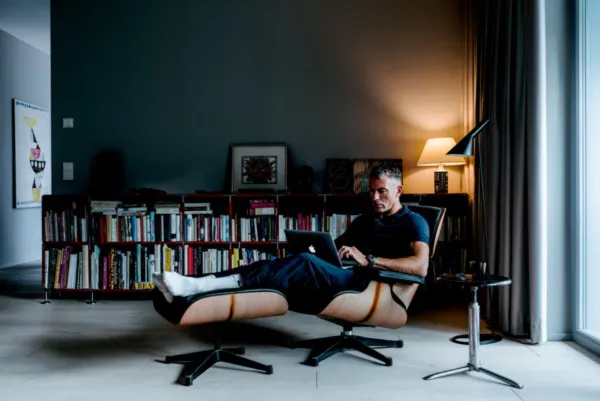 Un homme travaille sur un ordinateur portable dans une pièce élégante à l'éclairage tamisé, entouré de livres.