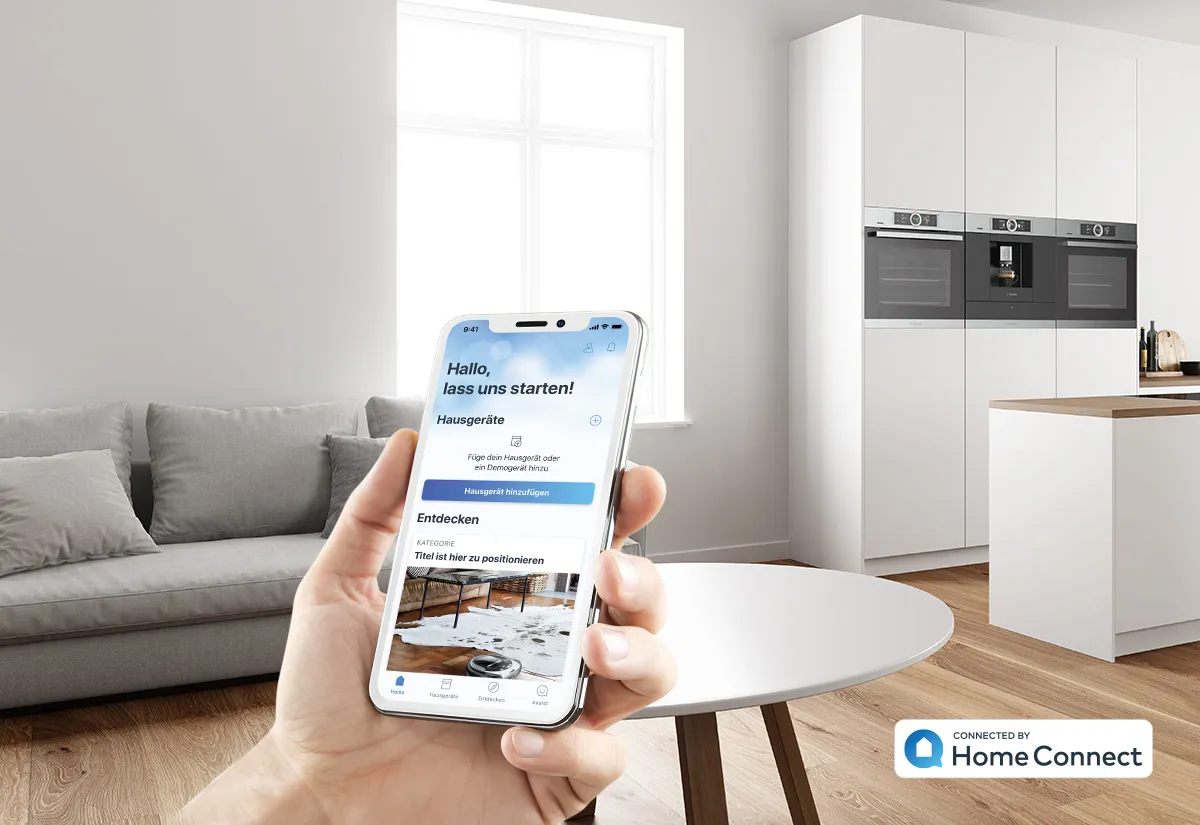 Eine Hand hält ein Smartphone mit geöffneter Home Connect App vor einer hellen, modernen Wohnküche.