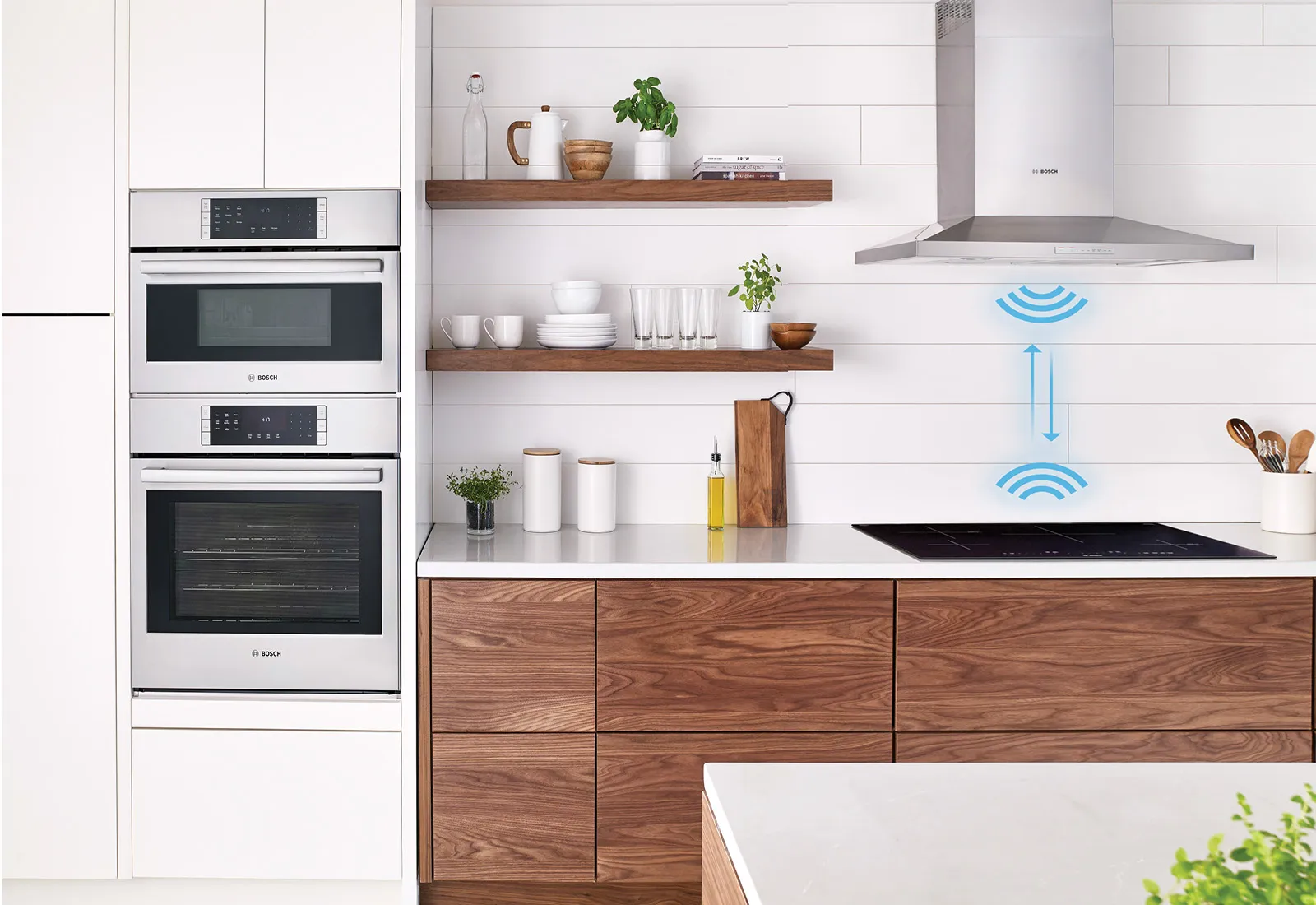 Cuisine moderne avec four encastré, four à micro-ondes, plaque de cuisson à induction avec capteur intelligent, armoires en bois, comptoirs blancs et étagères flottantes.