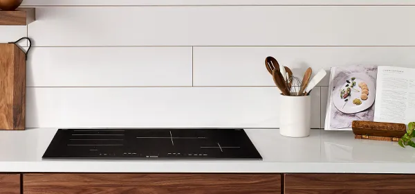 Bosch induction cooktop built into a white counter top with a dark brown wood cabinet