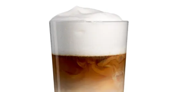 Glass of creamy coffee drink with foam on top.