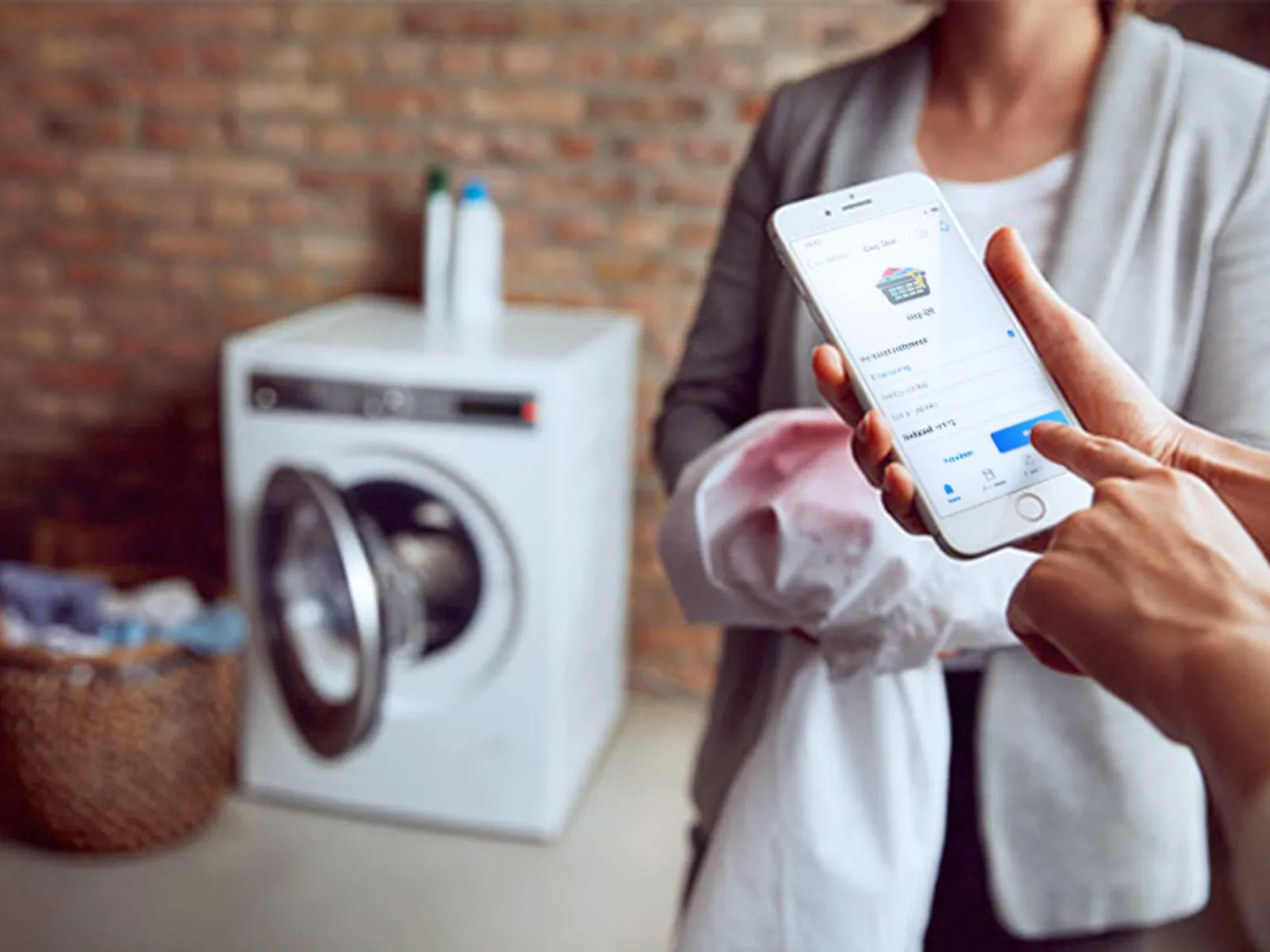 Person using home connect app in front of open washing machine