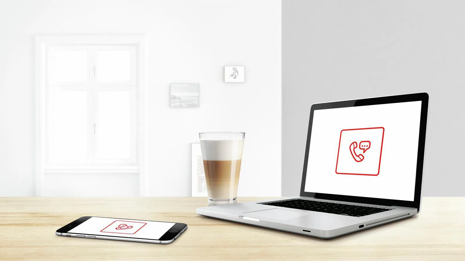 Laptop and smartphone displaying phone icon, coffee cup on wooden table, minimalist interior.