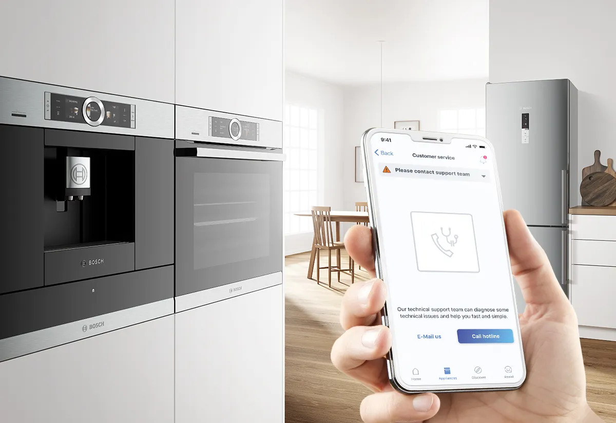 A smartphone displaying Bosch customer support on the Home Connect app, in front of sleek built-in appliances.