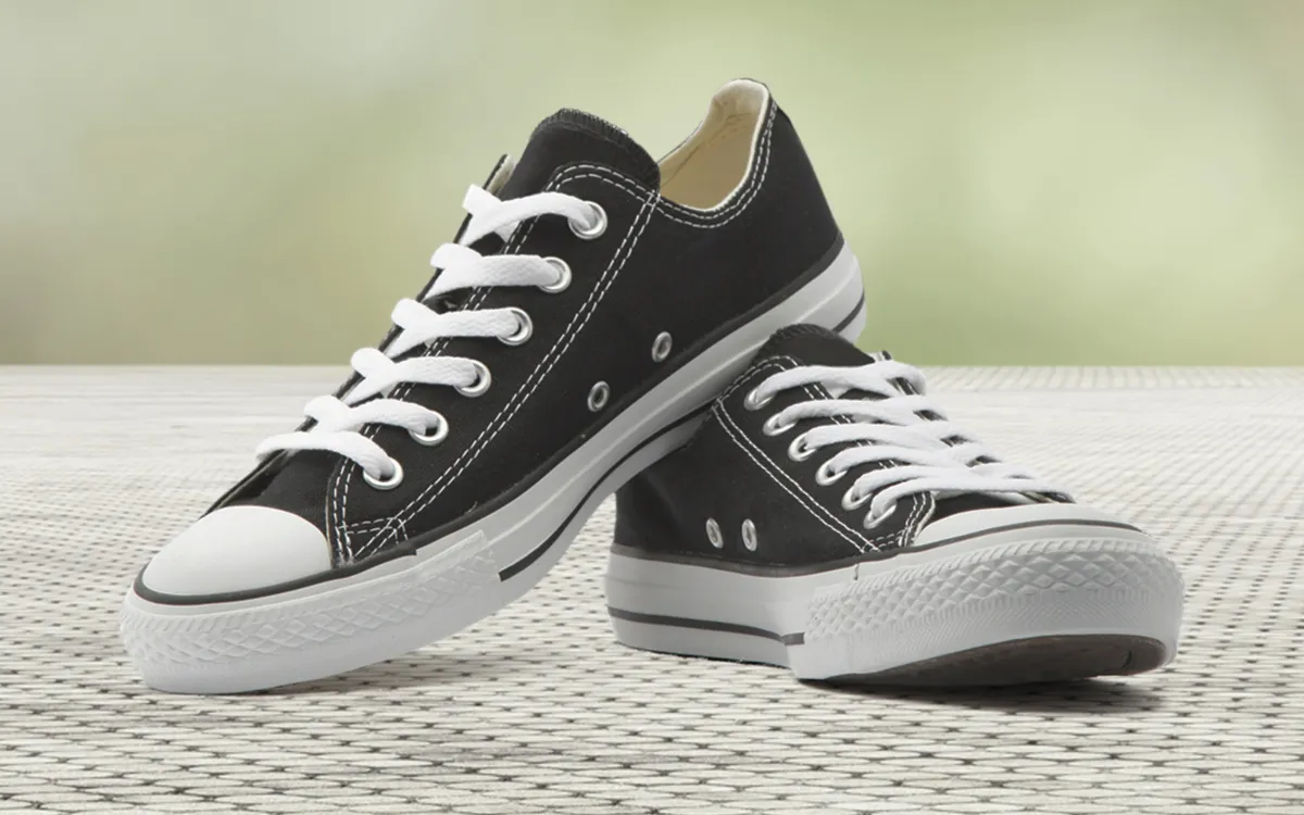 Black trainers with laces on the floor.