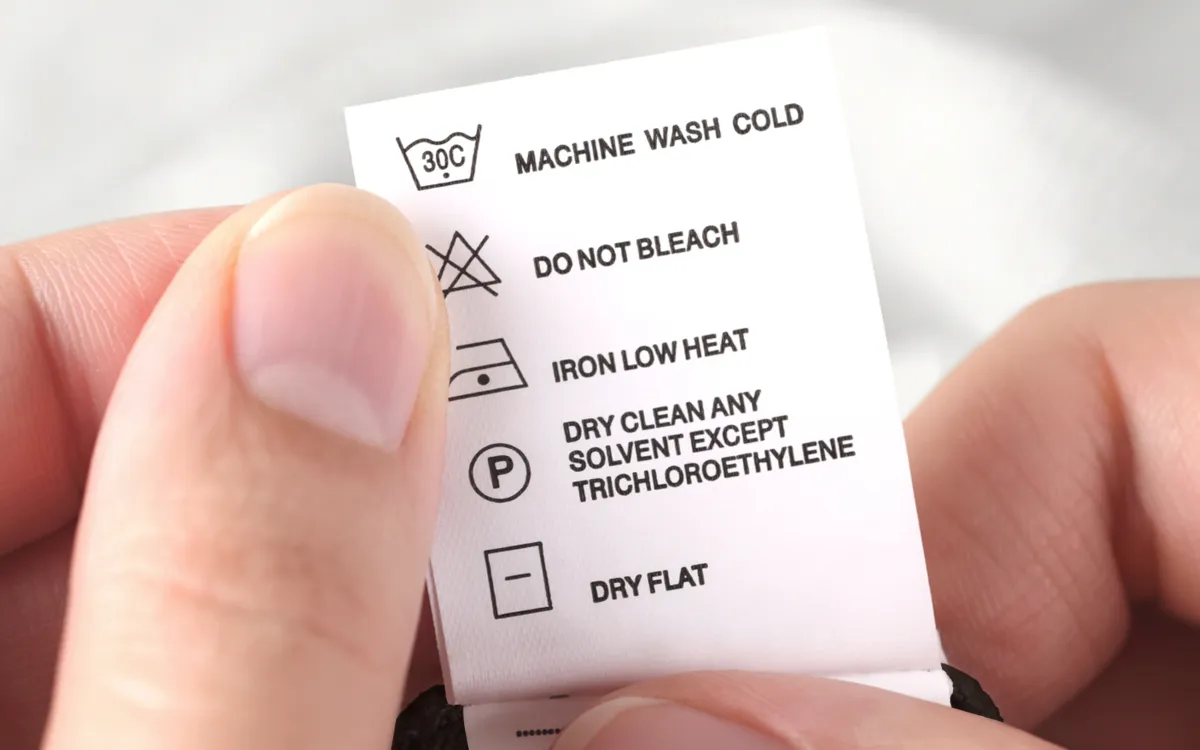 Clothing care label with instructions for machine wash cold, no bleach, low heat iron, and dry cleaning.