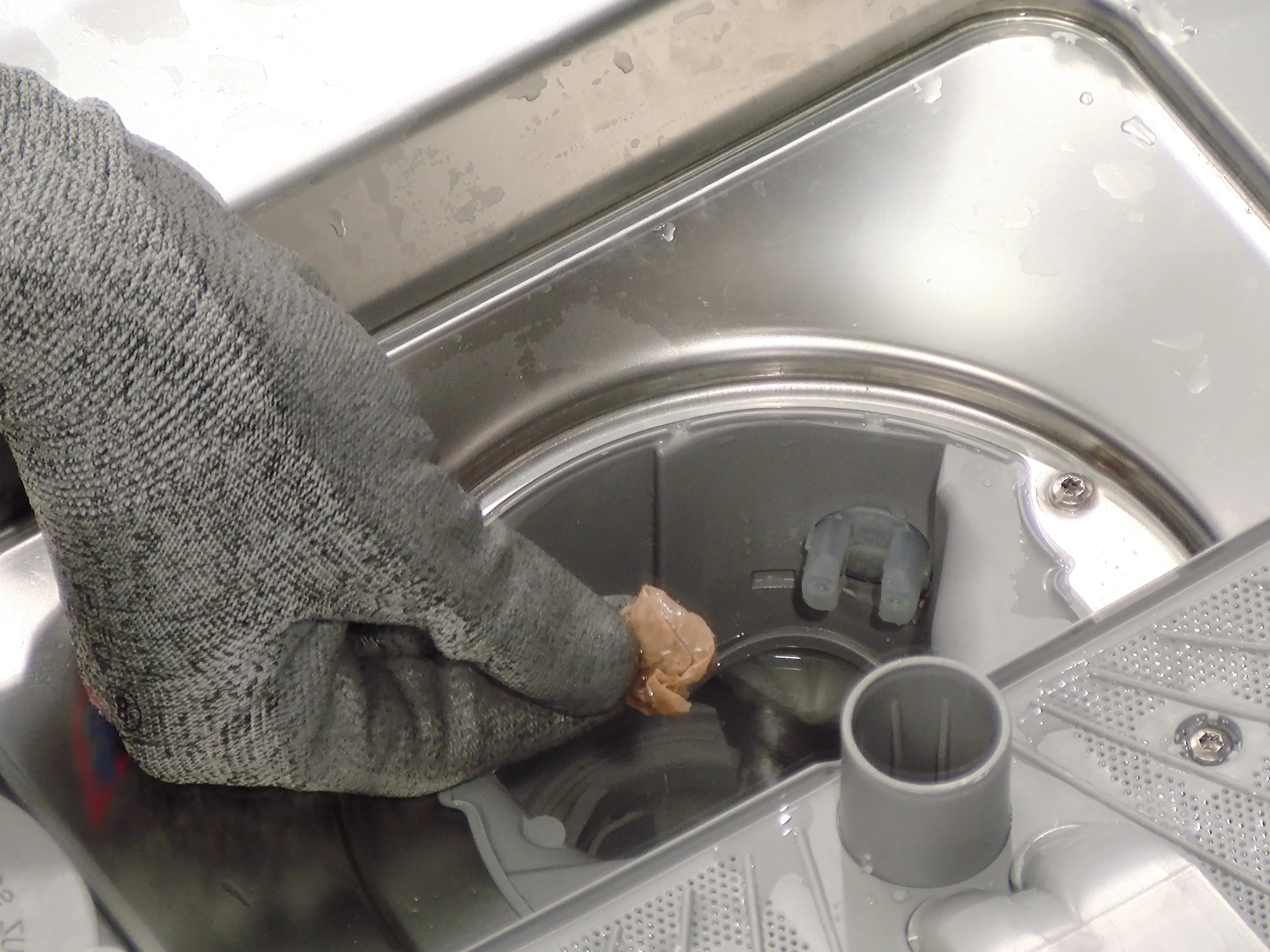 Person checking the pump of a Bosch dishwasher for foreign objects.