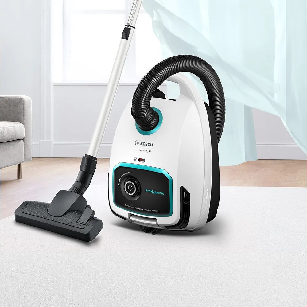 Прахосмукачка марка Bosch цвят бяло синьо с маркуч и накрайник за под в домашна обстановка.