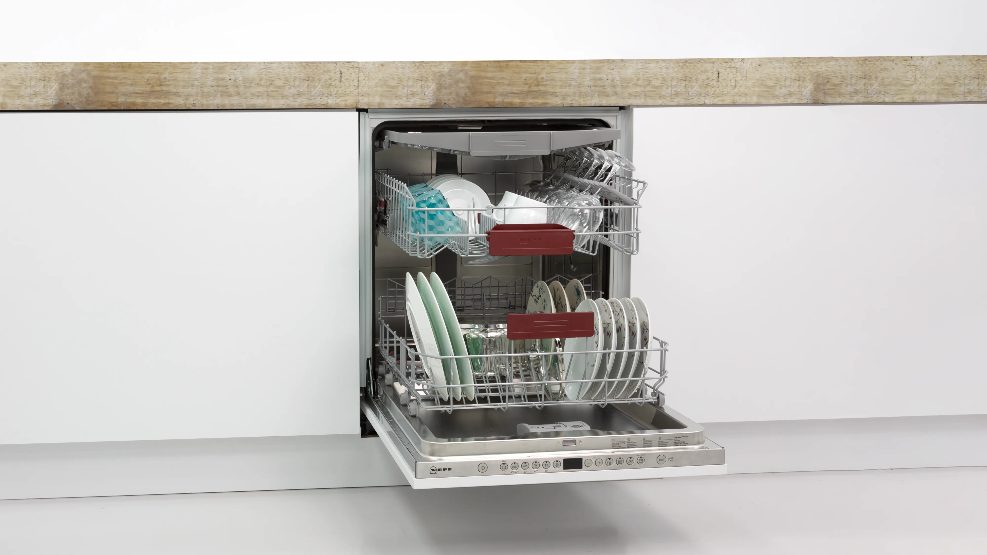 Open dishwasher with clean dishes and utensils inside.