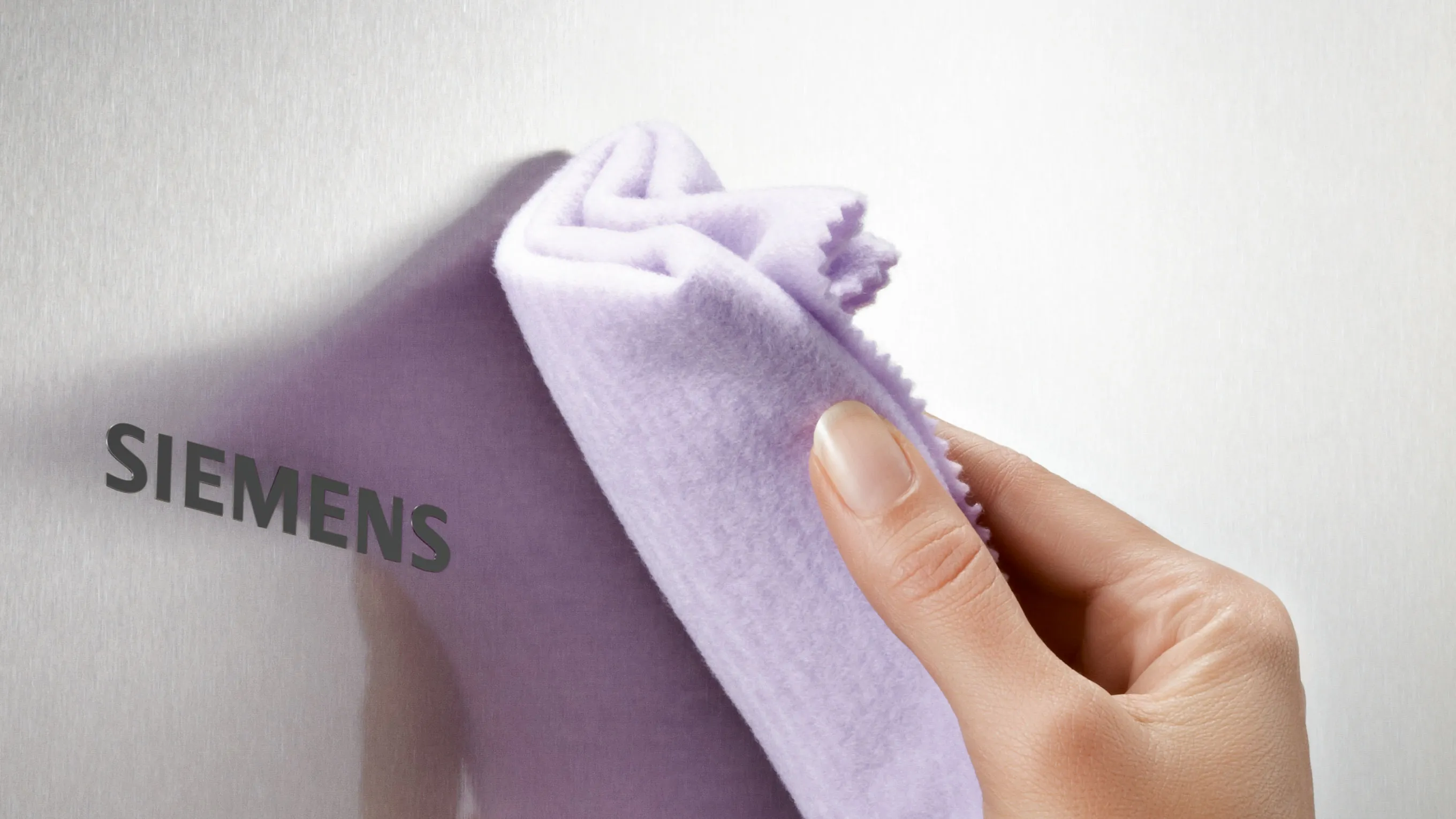 Siemens logo on a purple cloth being held by a hand.