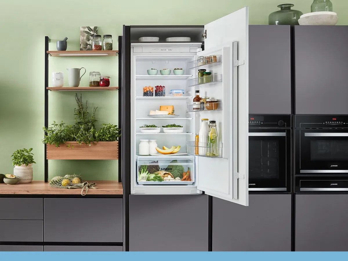 Moderne keuken met een open witte koelkast, gevuld met verse producten en drankjes, naast stijlvolle houten planken en zwarte keukenapparatuur.