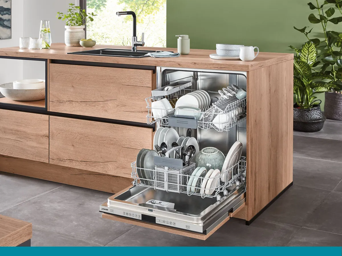 Een moderne keuken met een ingebouwde vaatwasser met servies en bestek erin, omringd door houten kasten en planten.