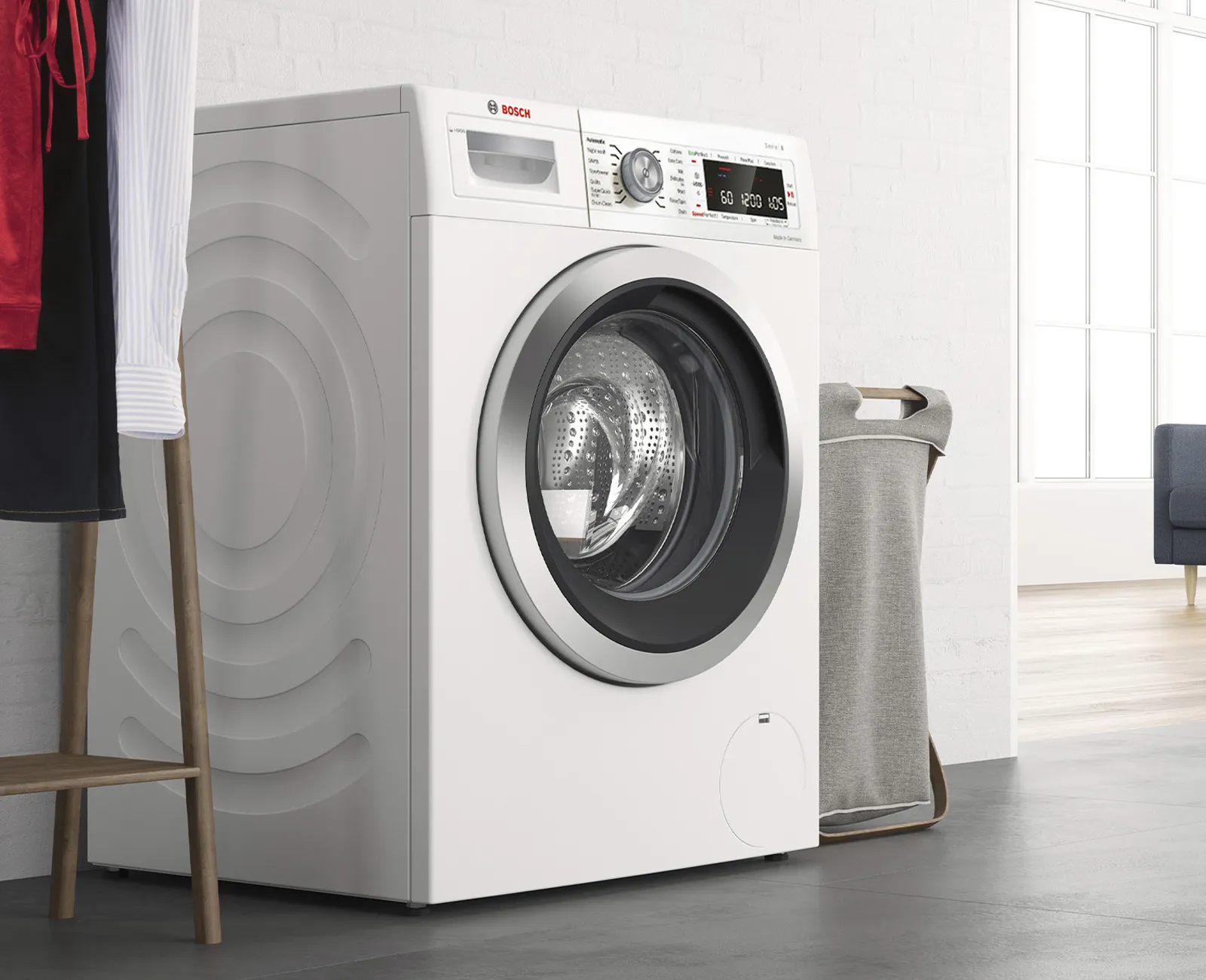 Washing machine in a modern laundry room with a red curtain and a gray towel.