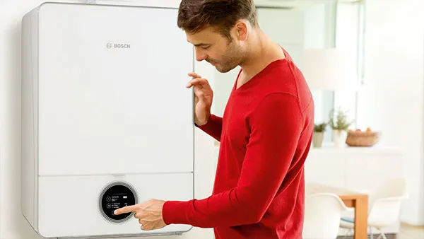 Hombre en suéter rojo examinando el aparato Bosch en la cocina.