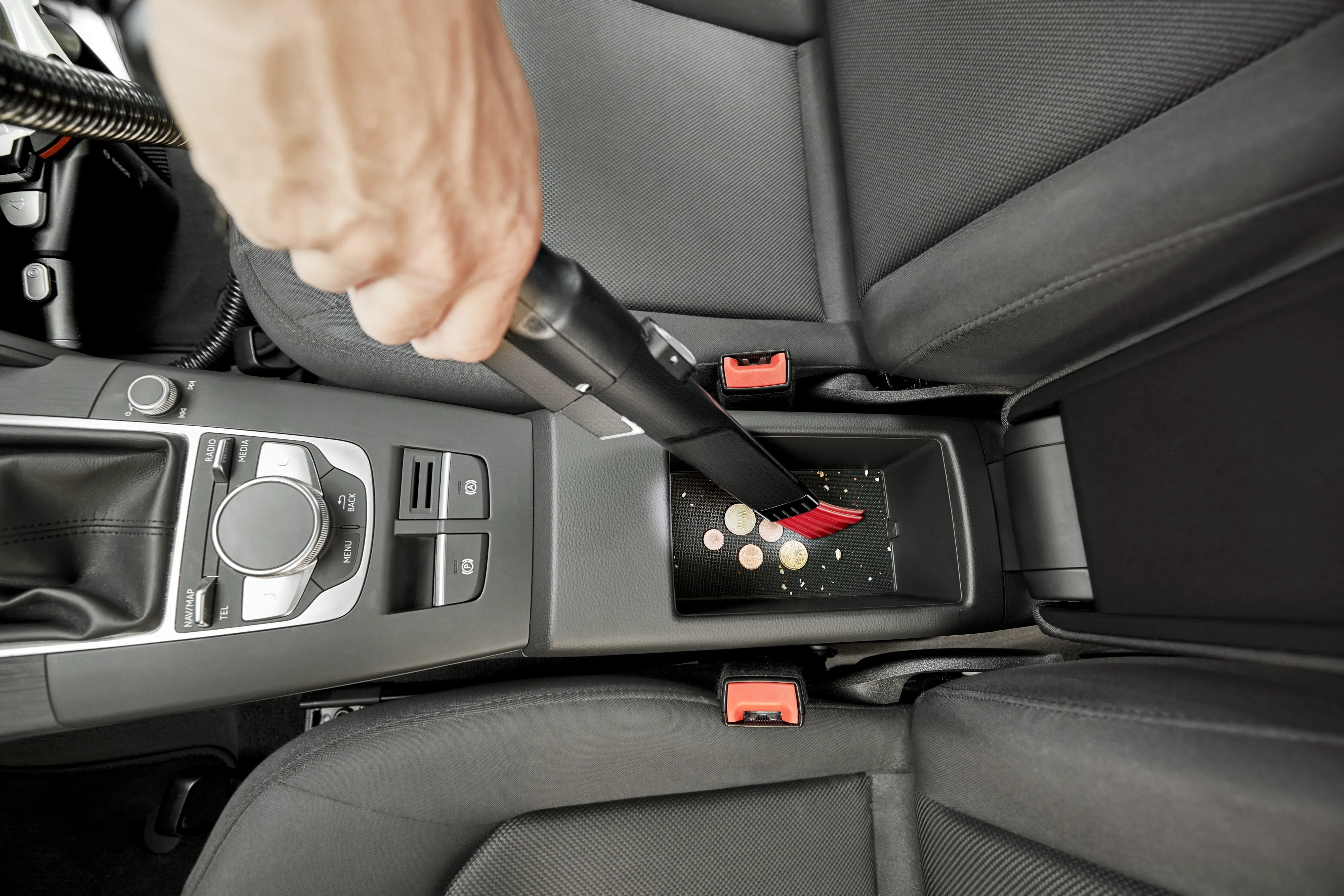 Person using vacuum attachment to clean between seats