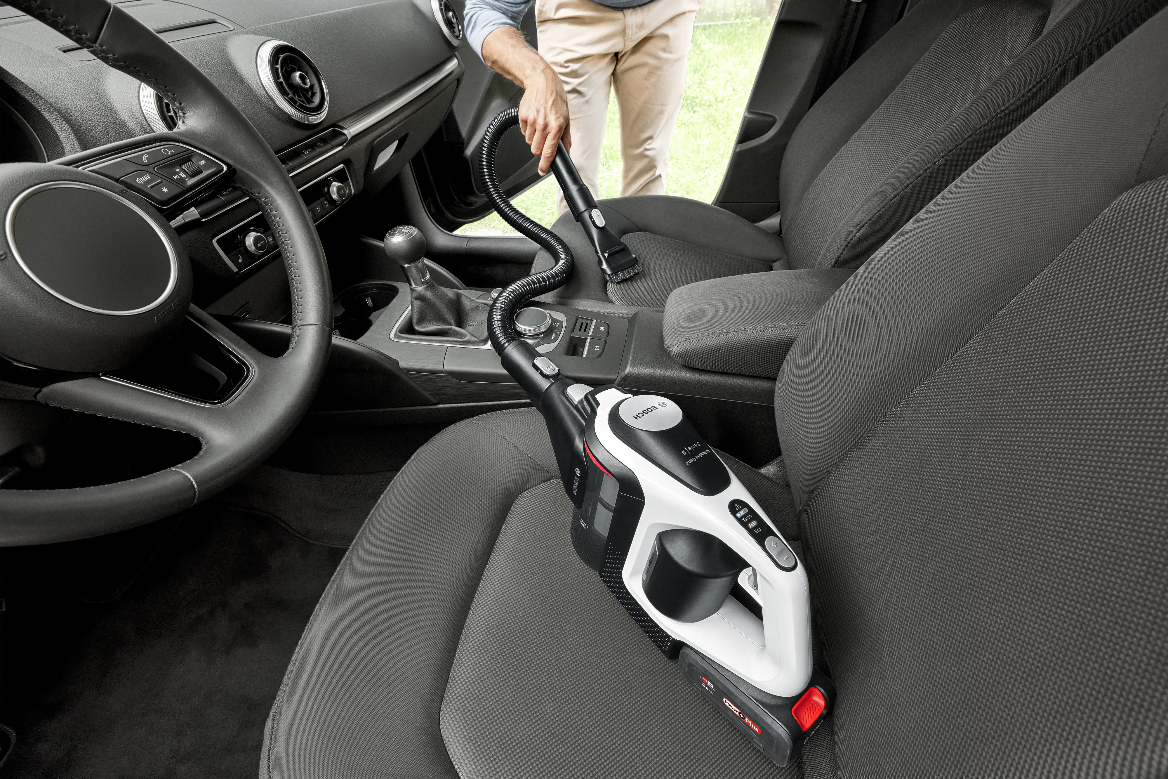 Person vacuuming car using flexible hose