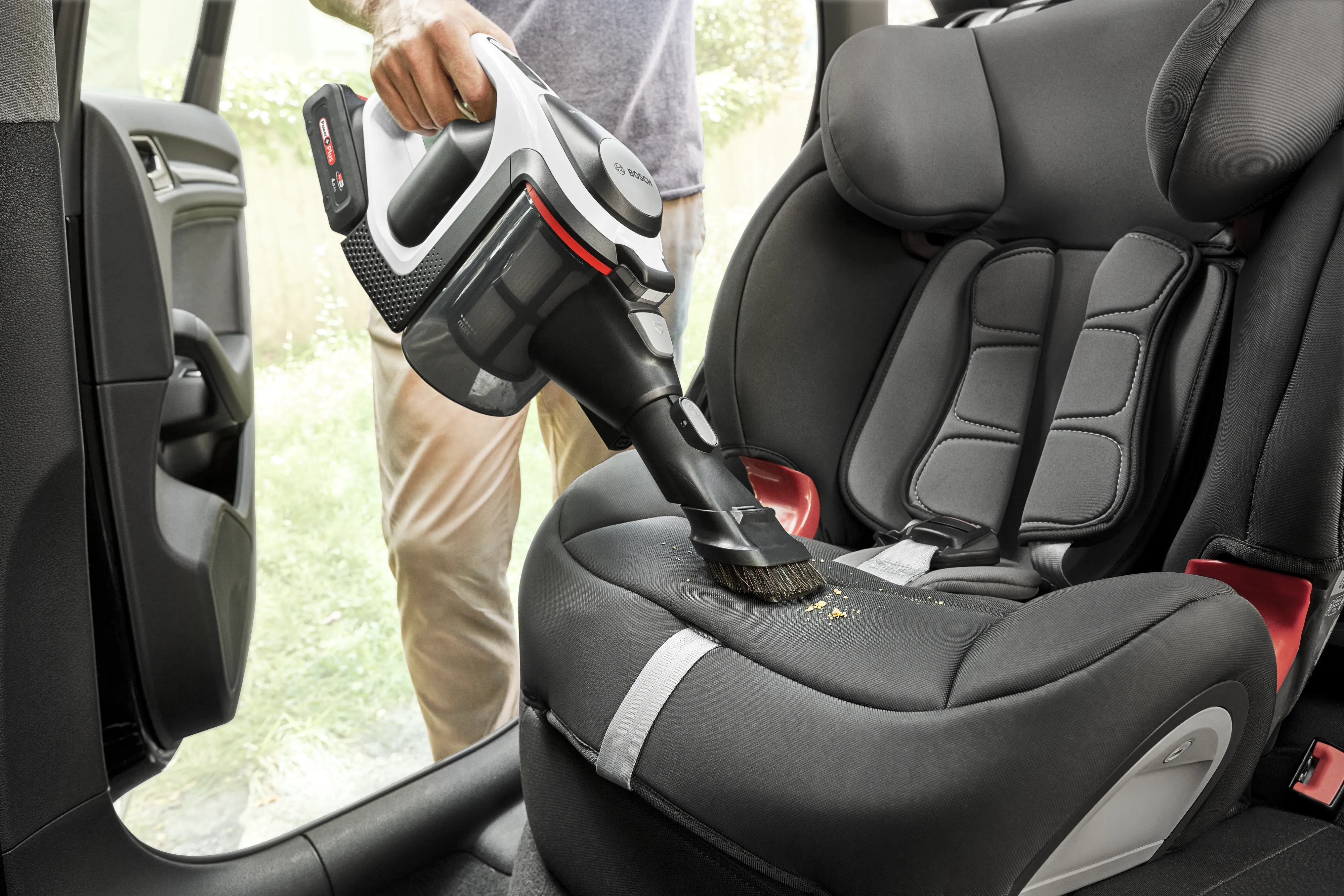 Person vacuuming car seat with lightweight vacuum