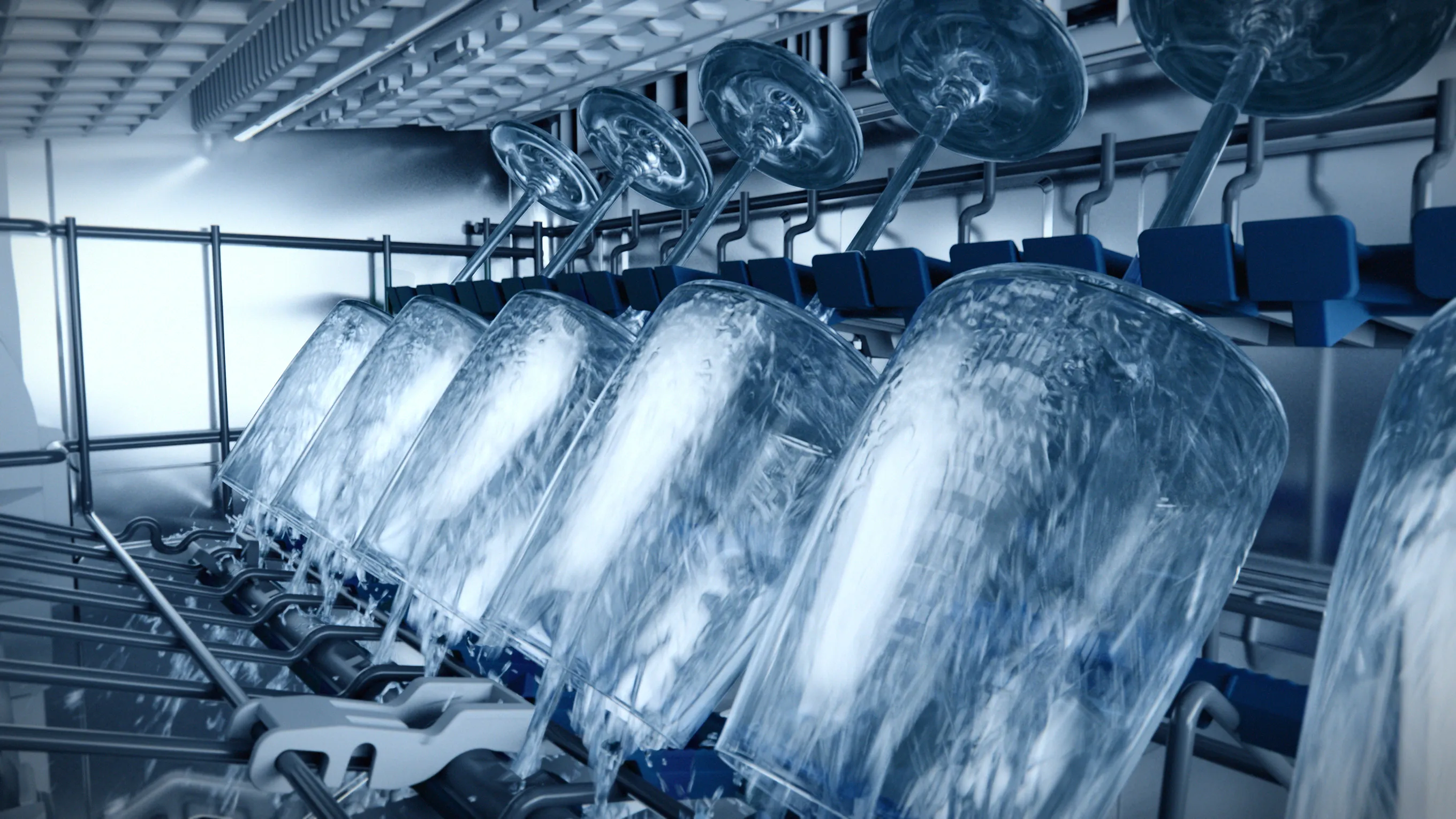 Industrial washing machine interior with rotating drums and water sprays.