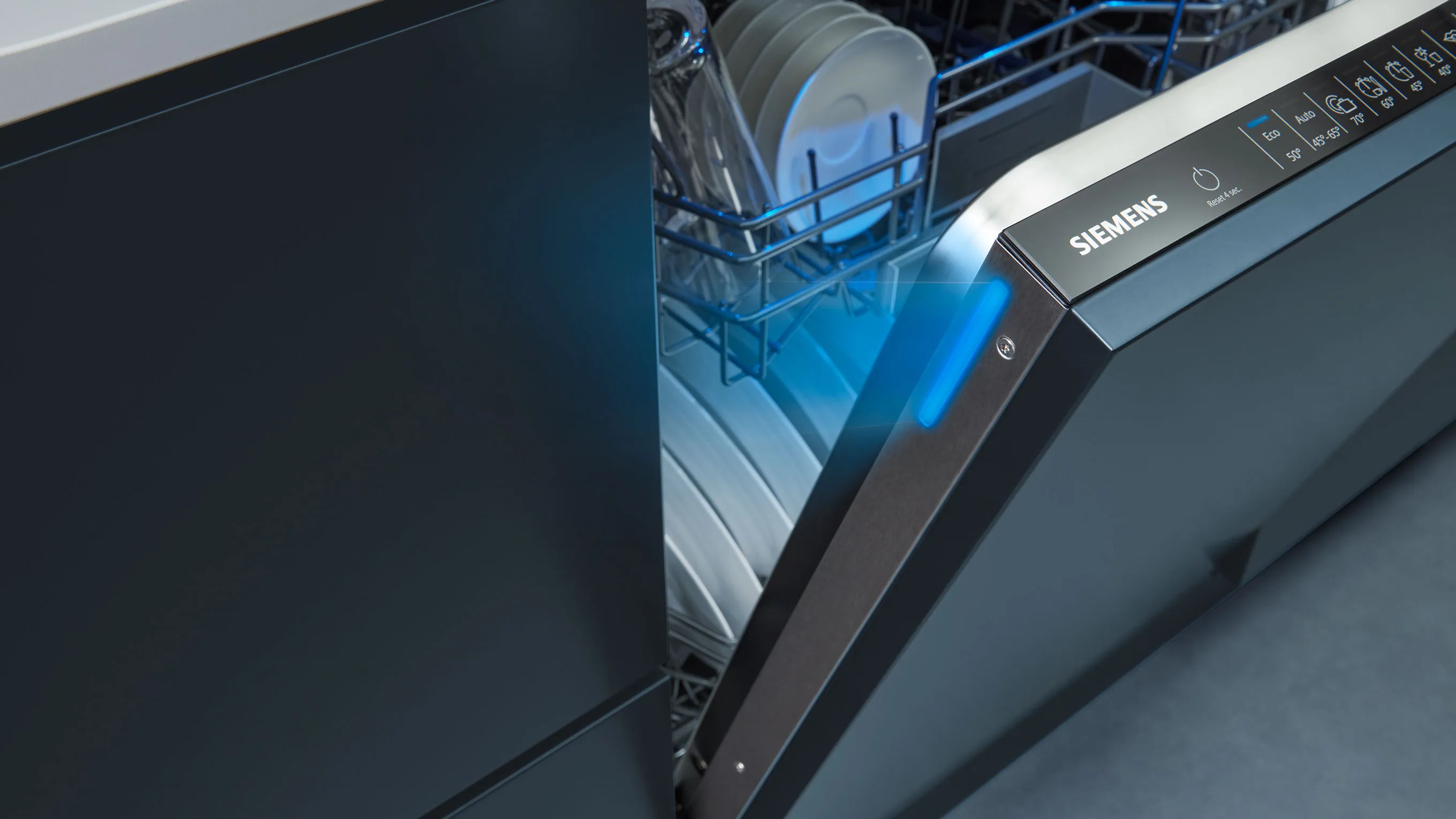 Geschirrspüler mit offener Tür, blaues Innenlicht und Regale für Geschirr.
