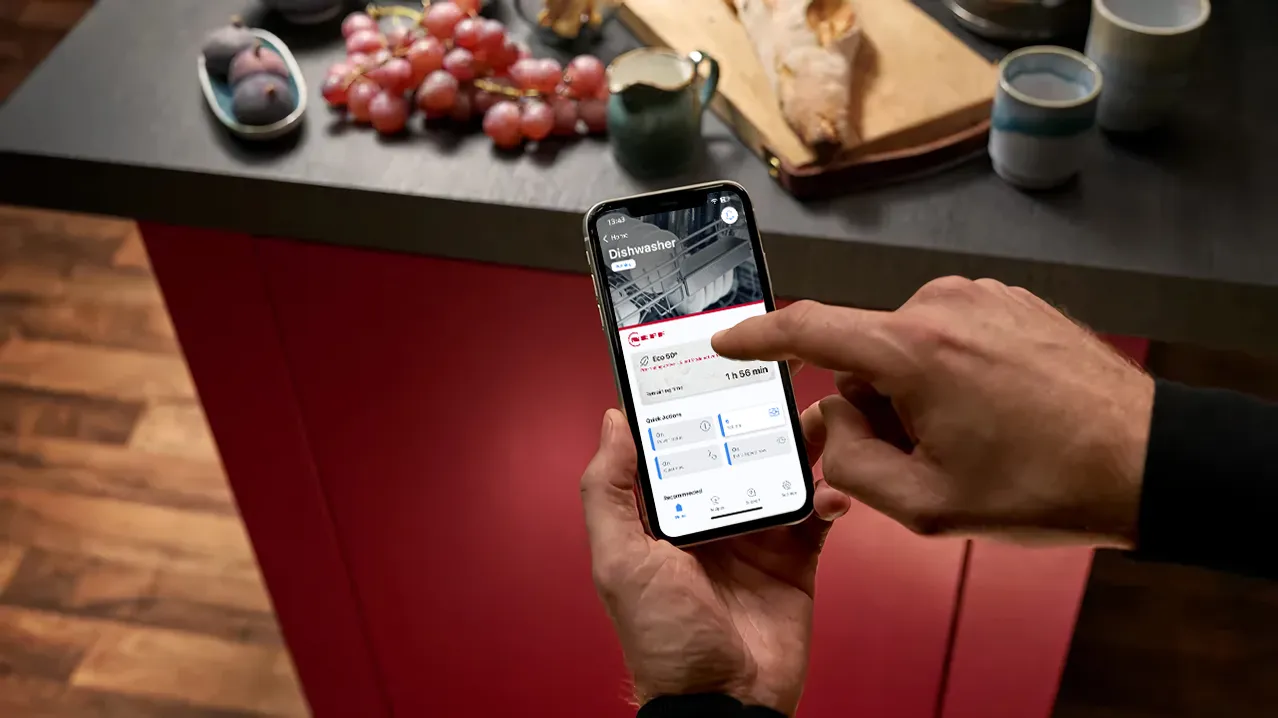 Persona che utilizza lo smartphone per monitorare i dati di fitness sul tavolo con snack sani.