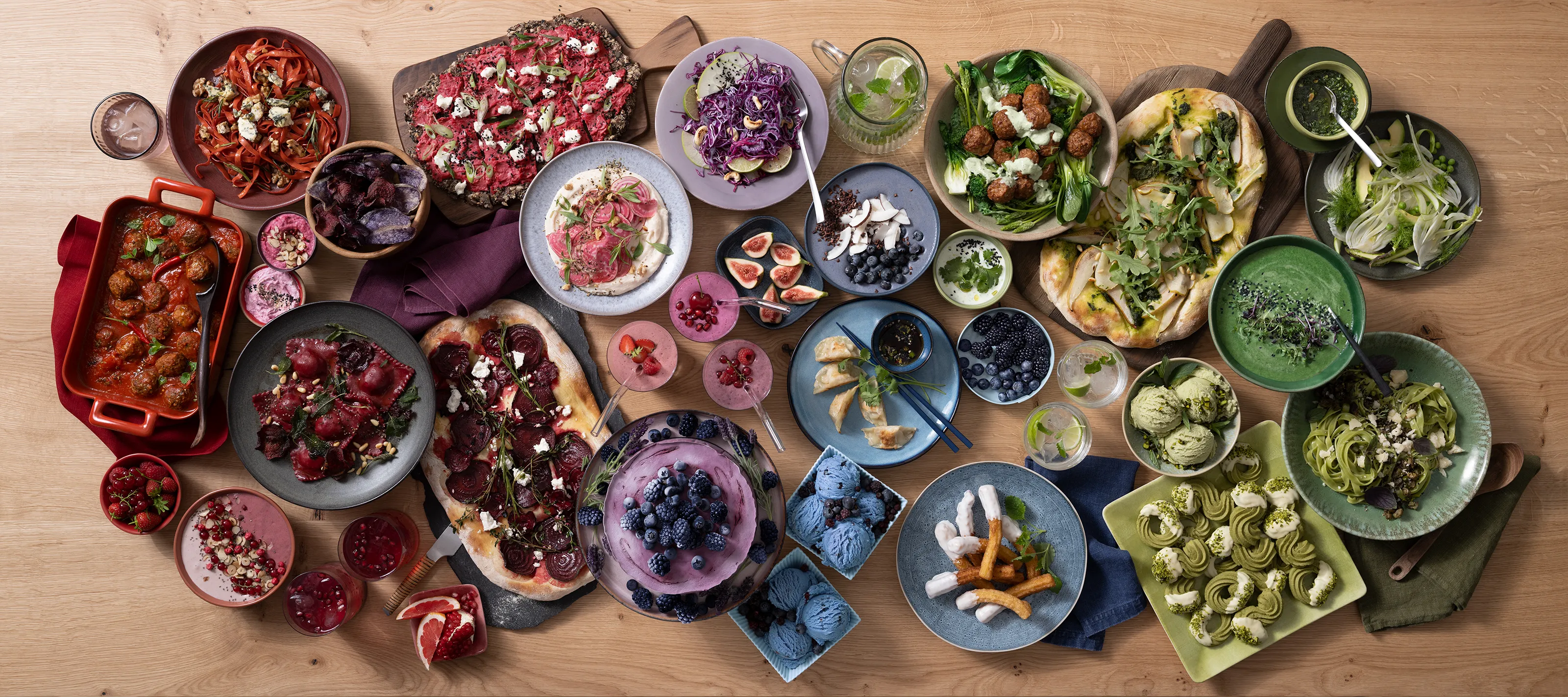 Masă de bucătărie vazută de sus pe care sunt așezate diverse preparate culinare, cu colorit variat