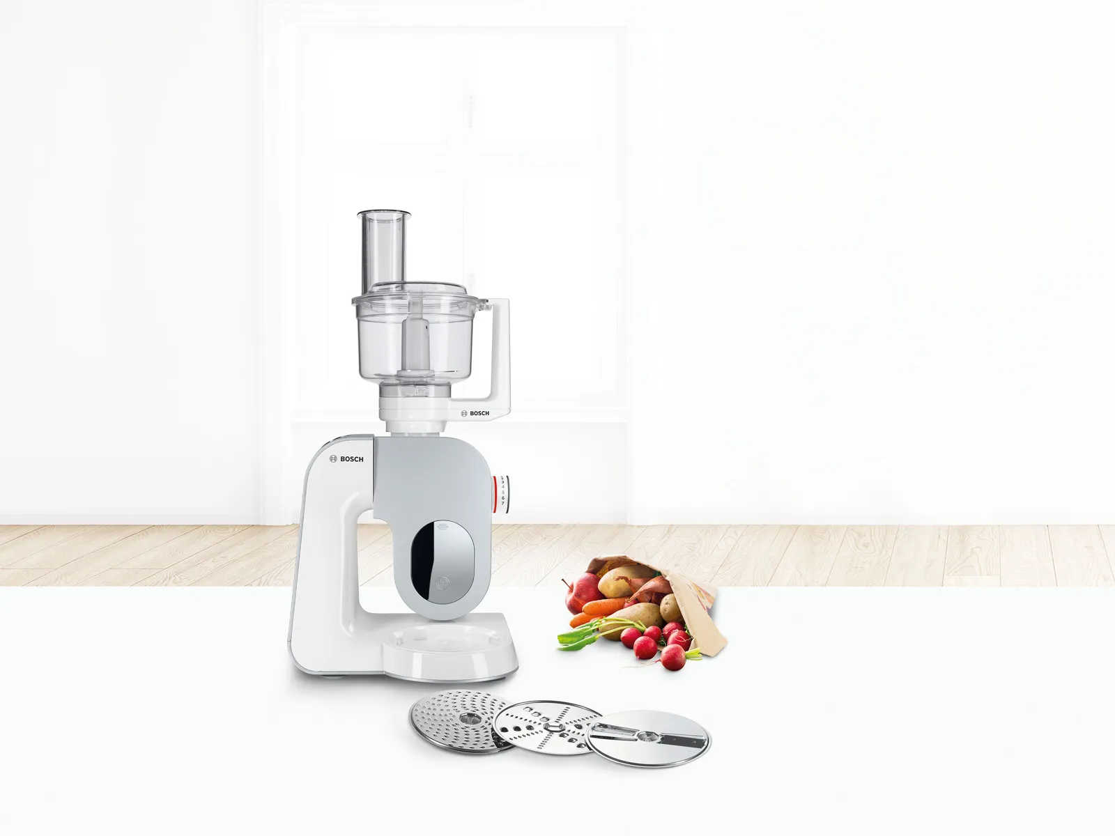 Robot de bucătărie cu accesoriu Multimixer alături de ingrediente neprelucrate si trei cuțite pentru accesoriu