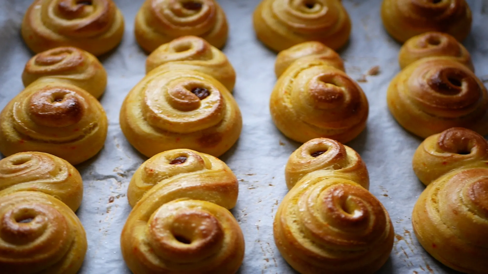 En plåt med nygräddade kanelbullar som har gyllene färg och snurriga mönster, redo att avnjutas.