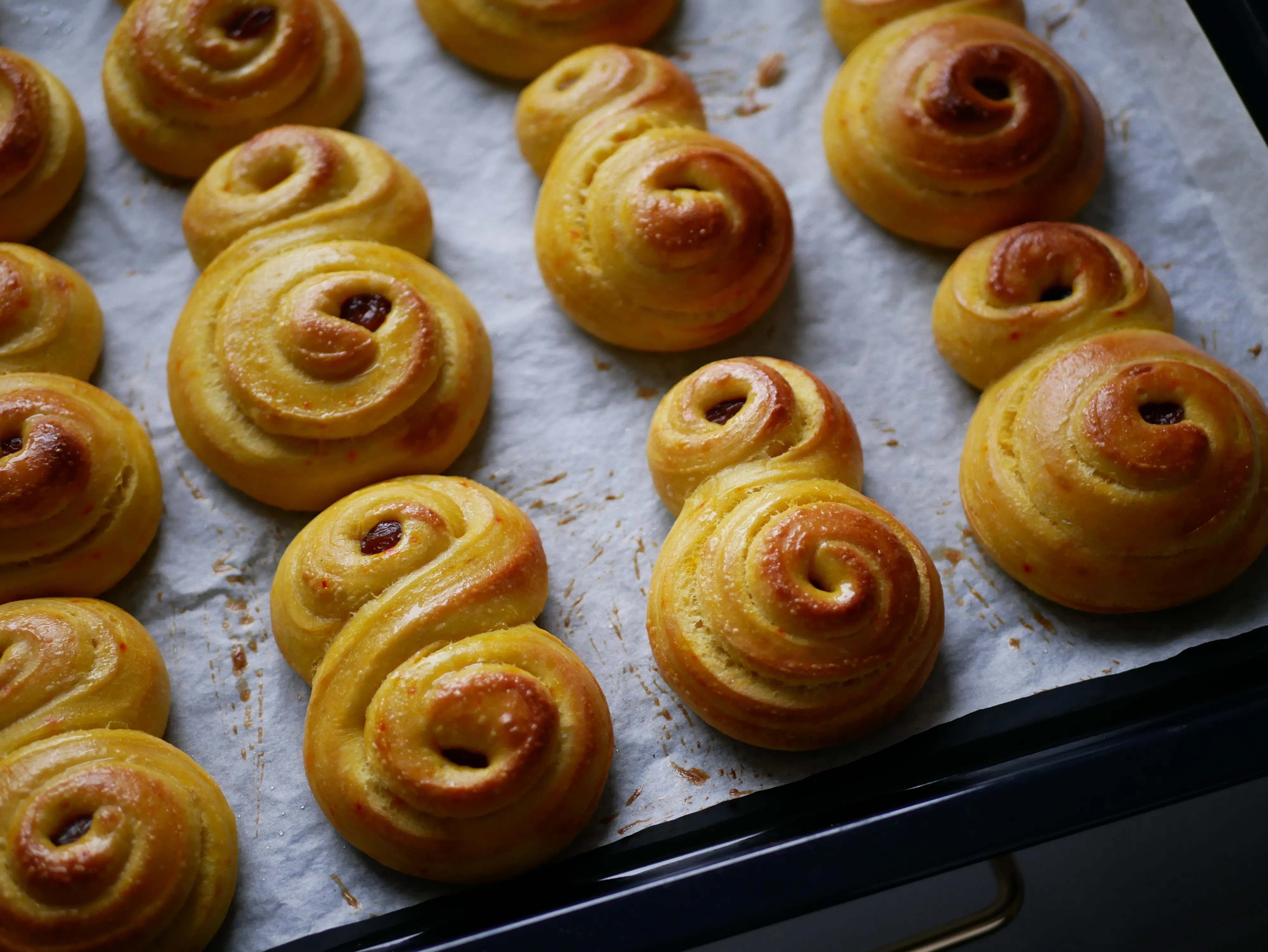 En bakplåt fylld med nygräddade snurrade bullar, gyllene och doftande, perfekta som godsaker.