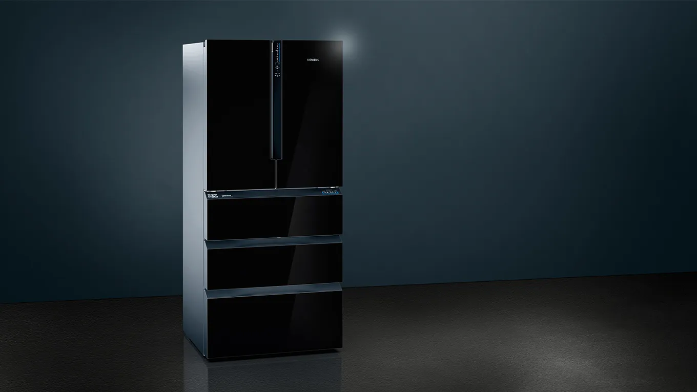 Black refrigerator with multiple doors and drawers in a dark room.