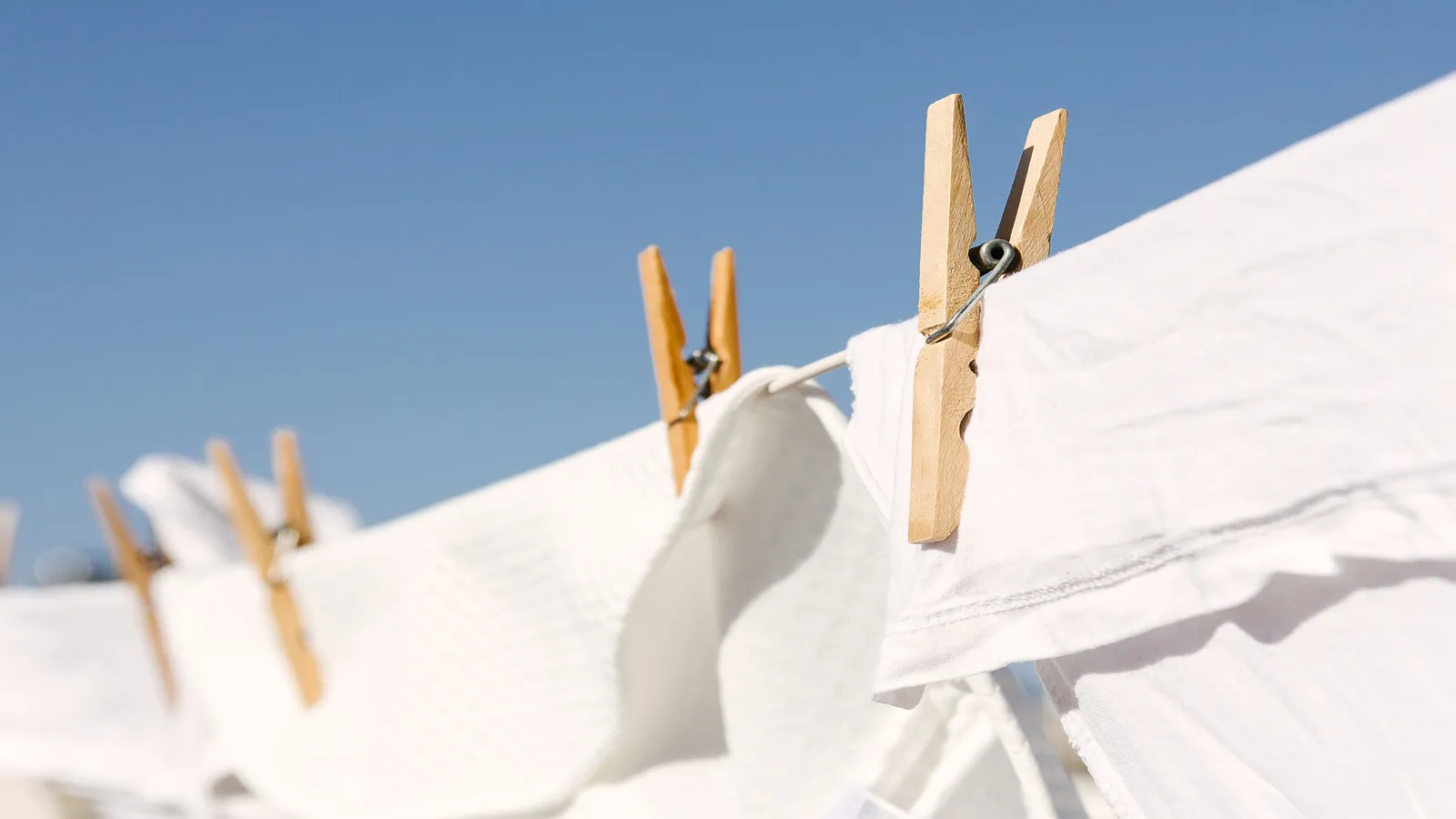 Clothespins on a clothesline against a clear blue sky.