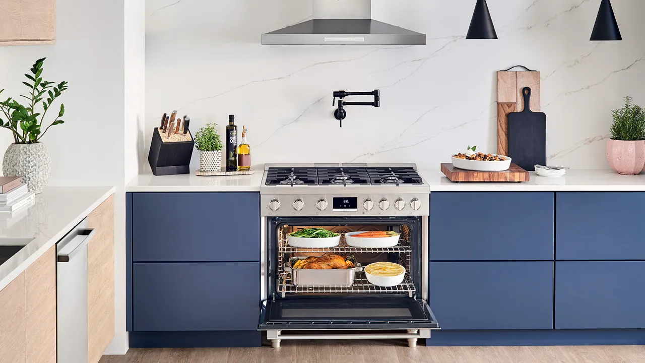 Modern kitchen with a Bosch stainless steel oven, open and filled with various cooked dishes.