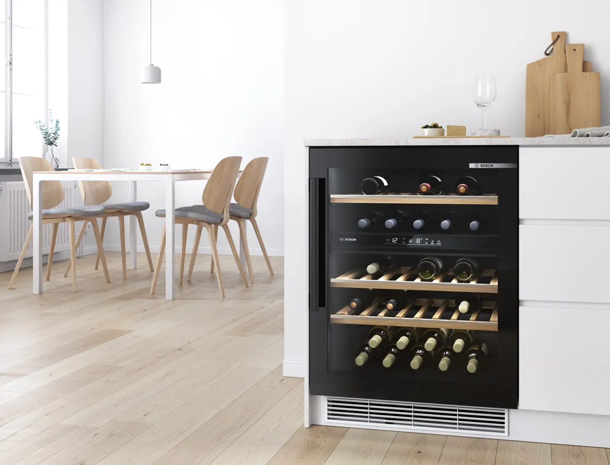Built-under wine cooler with two temperature zones and a small minimalist dining room with Scandi-style seating in the background