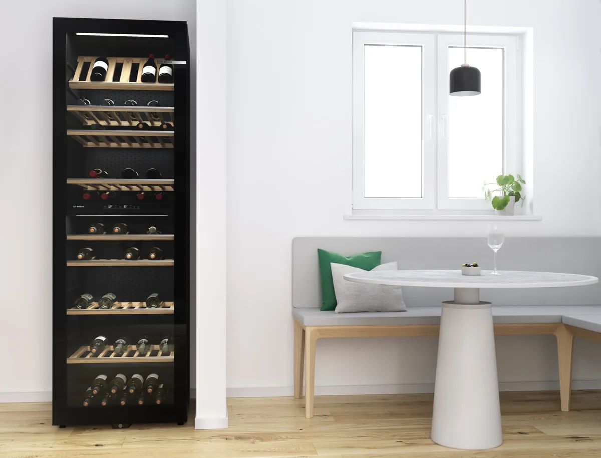 Large freestanding wine cabinet with several wines bottles on wooden racks next to a modern kitchen nook