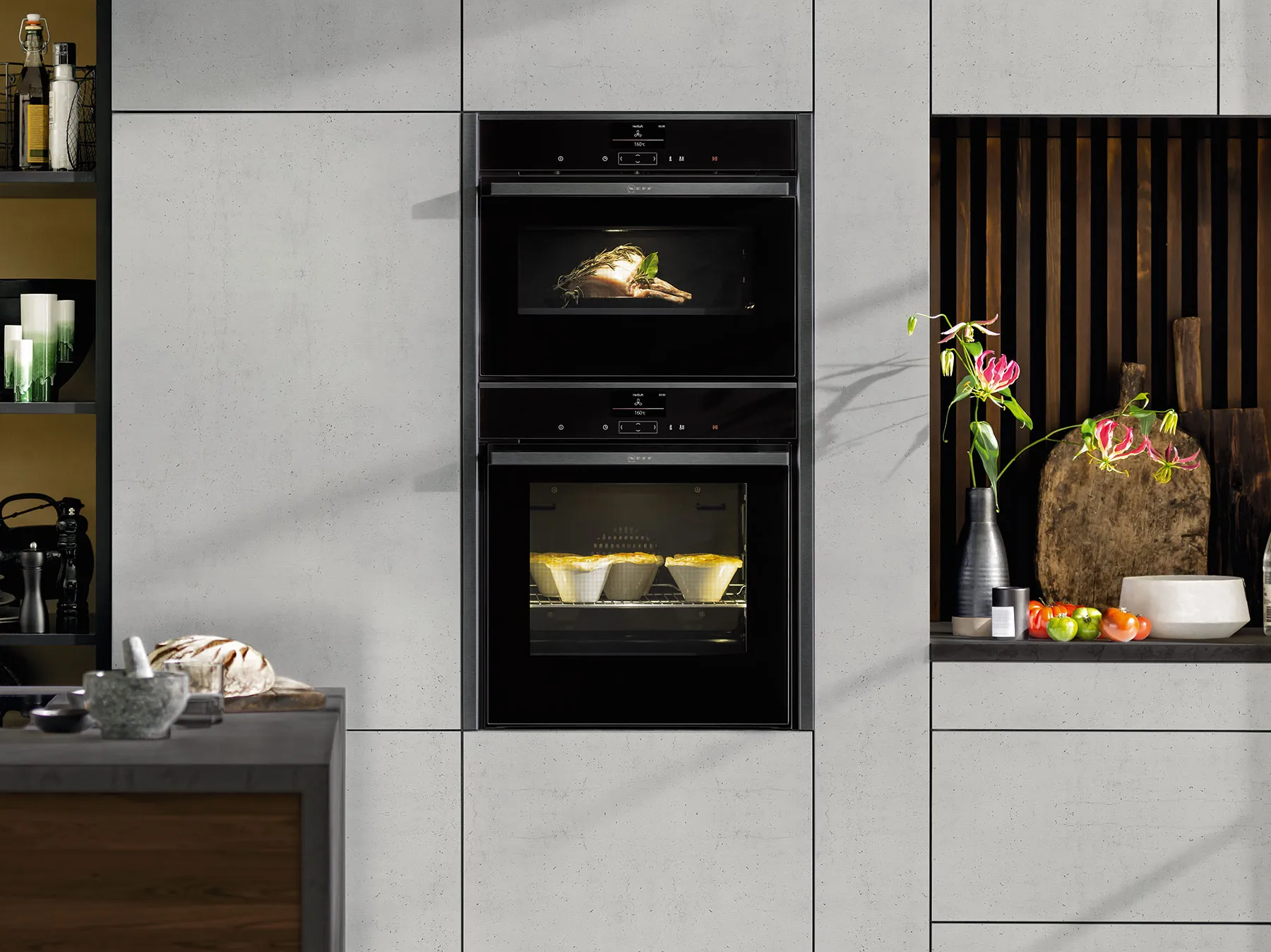 Image d'un four à micro-ondes empilé au-dessus d'un four, avec une combinaison sans couture en bronze brossé, dans une cuisine en bois brun foncé.