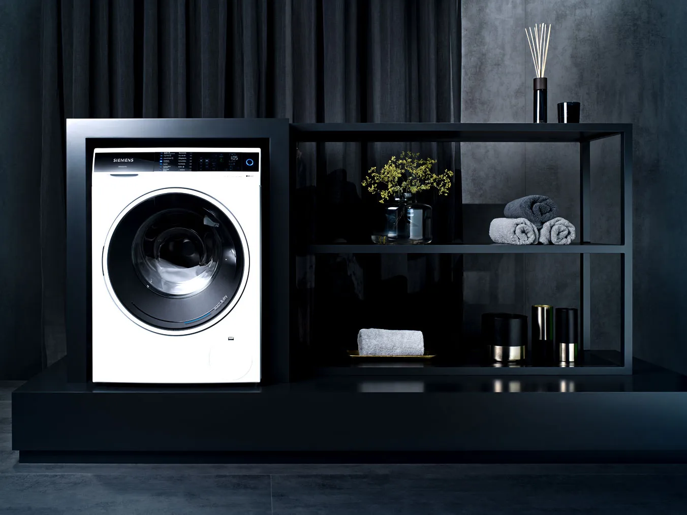 Modern washing machine, shelving unit, decor items, dark minimalist interior design.