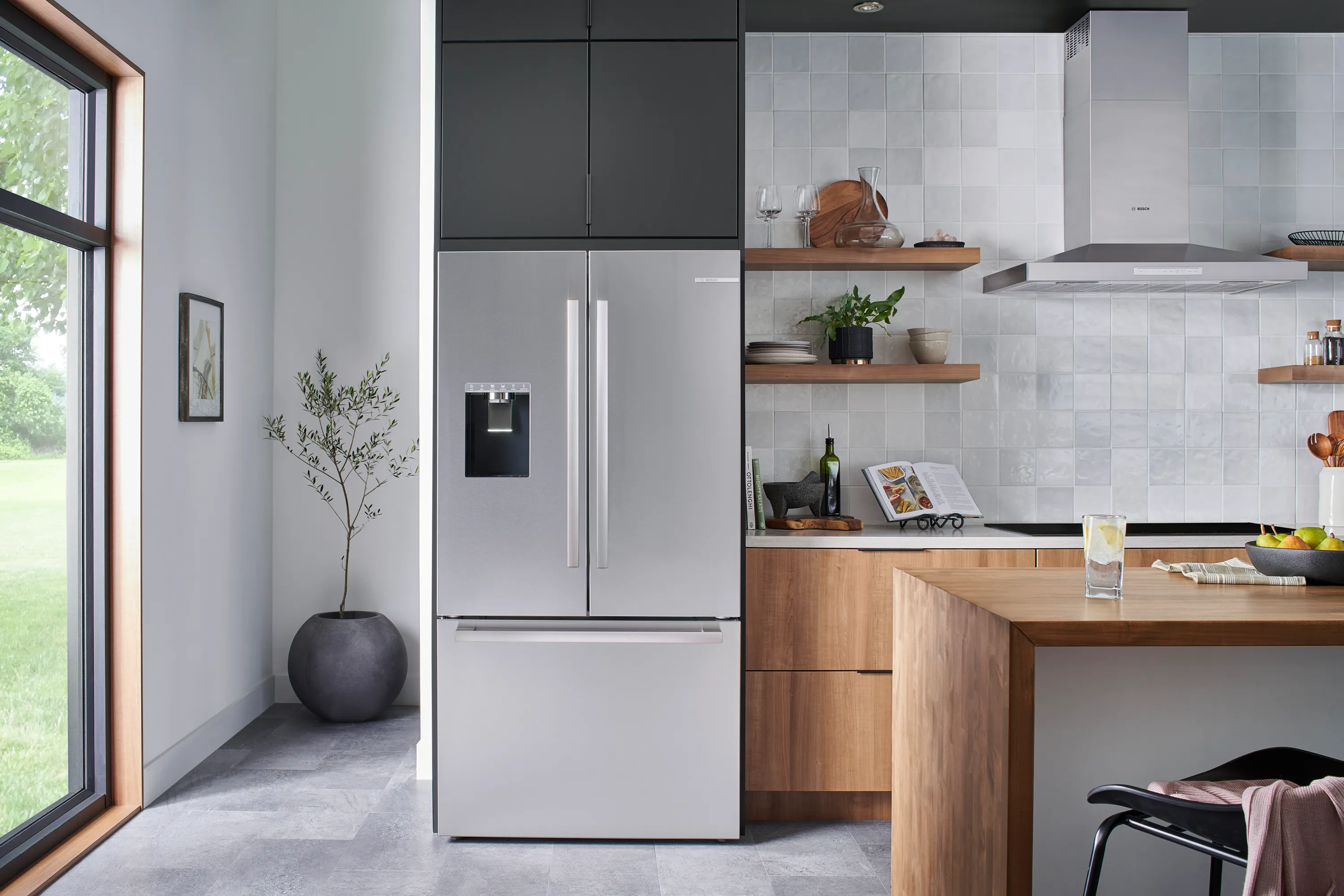 Modern kitchen with a Bosch stainless steel fridge-freezer and built-in water dispenser and Bosch Stove top and vent on the side