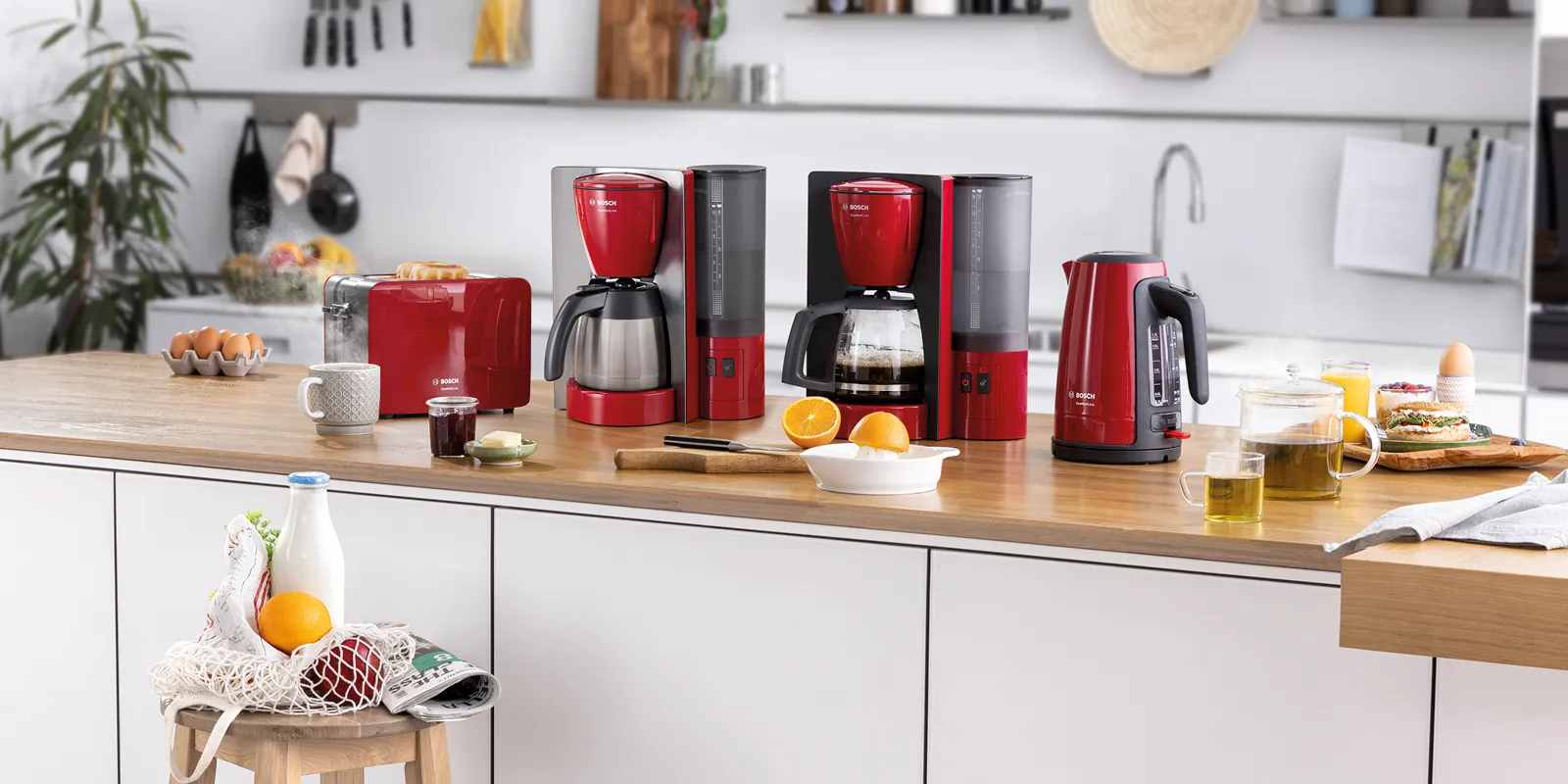 Qırmızı və paslanmayan poladdan hazırlanmış ComfortLine dəsti toster, filtrli qəhvə maşını və çaydanı ilə. Masanın üzərində səhər yeməyi üçün məhsullar