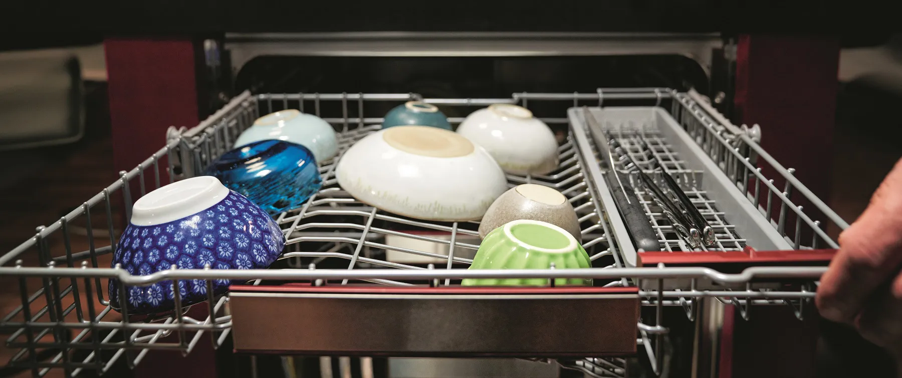 Geschirrspüler mit verschiedenen Geschirr, Schüsseln und Küchenutensilien.