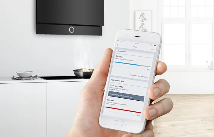 Modern mutfakta ev otomasyon uygulaması ile akıllı telefon tutuyor.