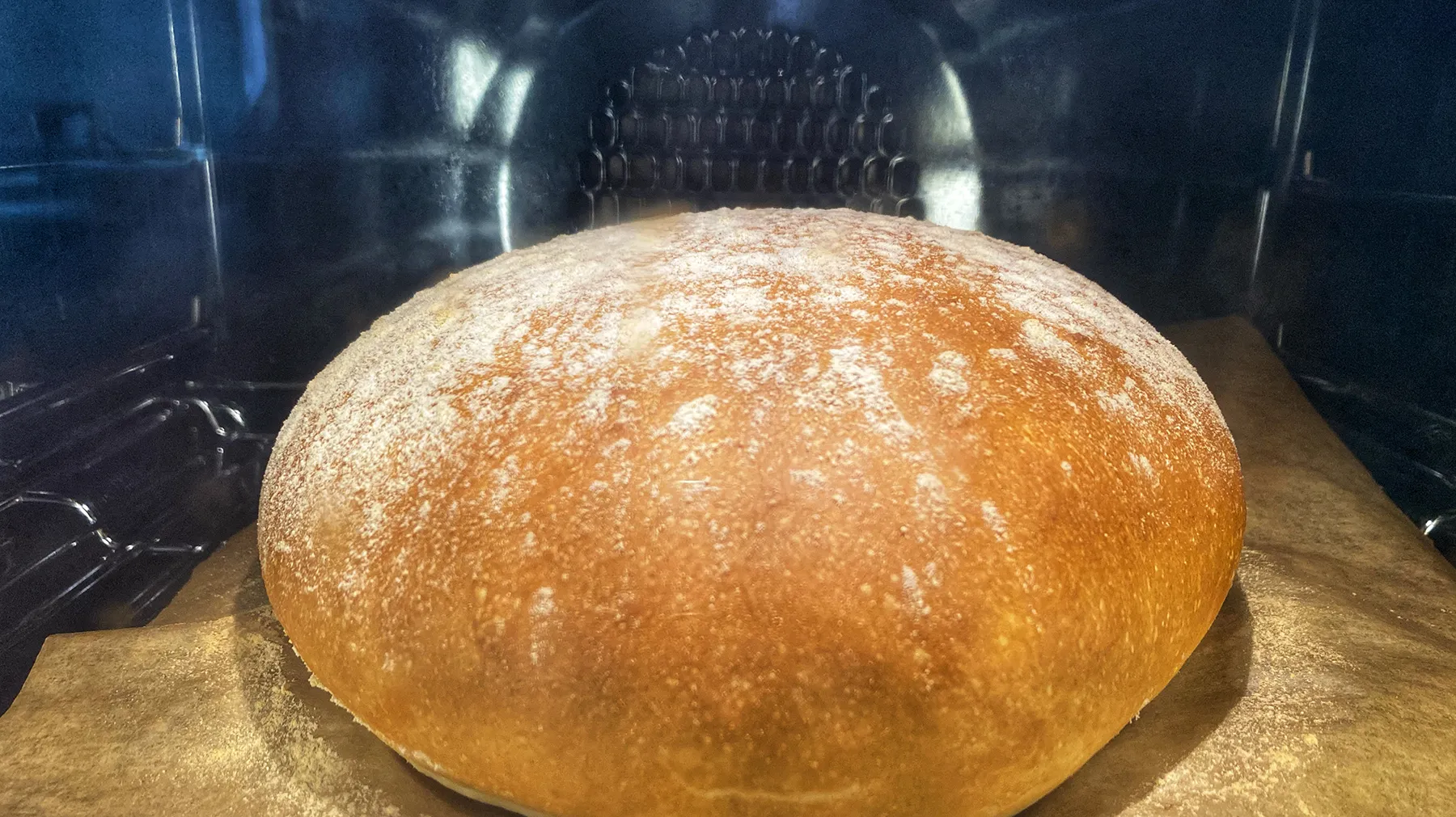 Frisch gebackene Runde Brot in Ofen, goldene Kruste, Holzoberfläche.