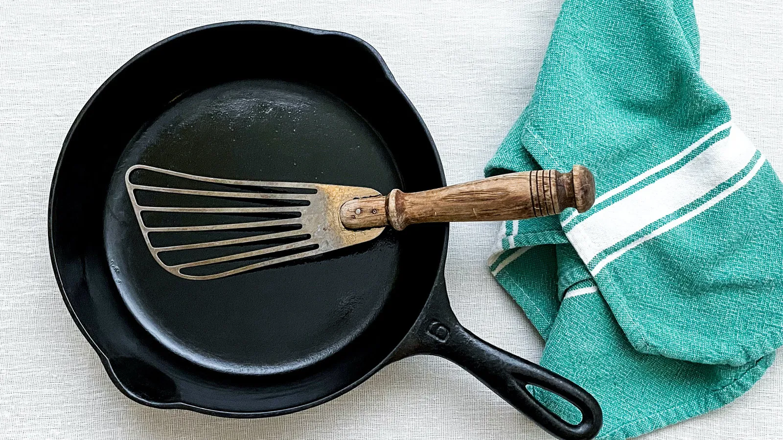 Pan with dirty looking utensil on top with towel next to it