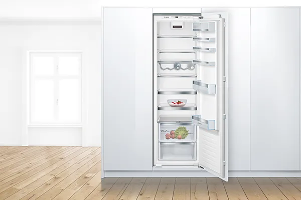 Fridge freezer with open door in a tall kitchen unit