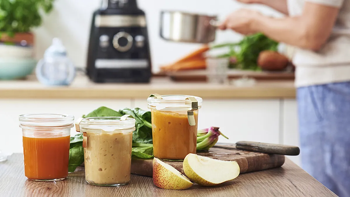 Healthy smoothies, fresh produce, kitchen appliance, wooden table, cooking preparation.